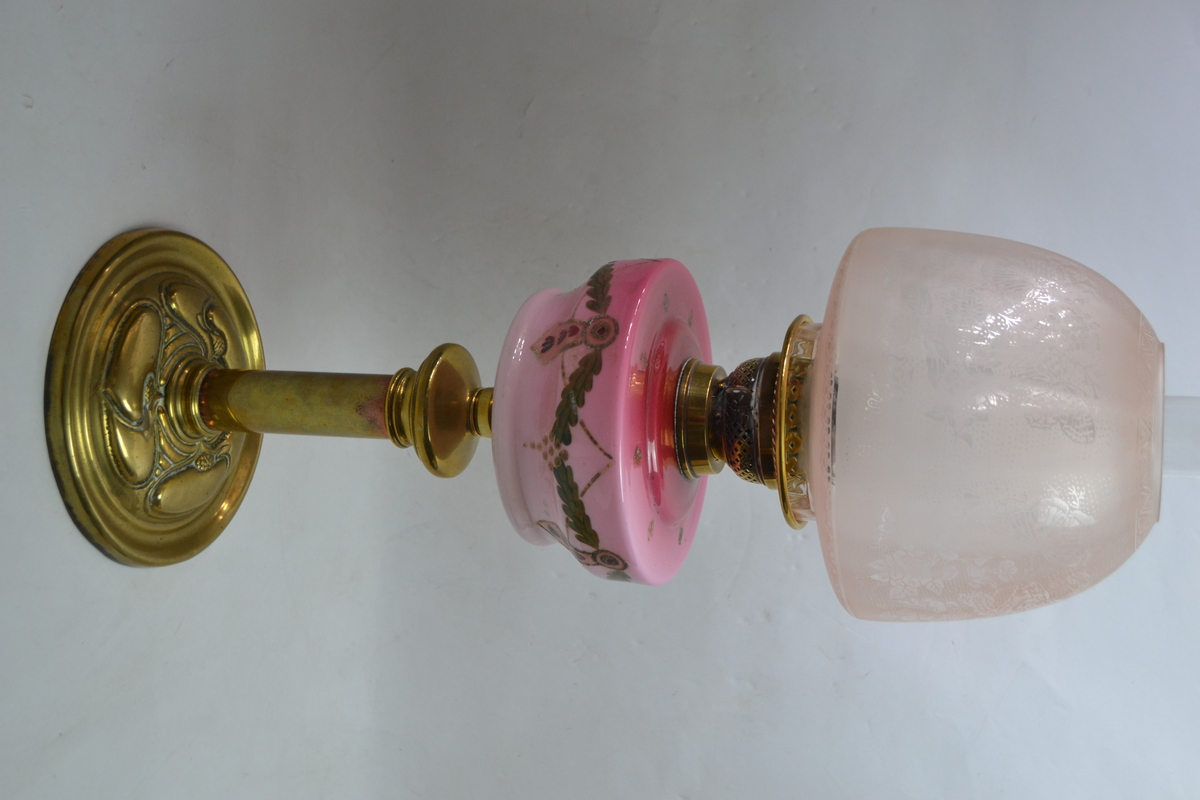 An Art Nouveau Brass Based Oil Lamp With Enamel Painted Cranberry Ceramic reservoir